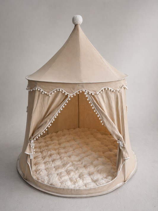 Beige children's play tent with pom-pom trim on a gray background