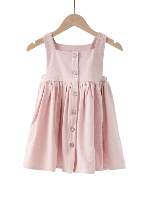 Pink dress with buttons on a wooden hanger against a light blue background