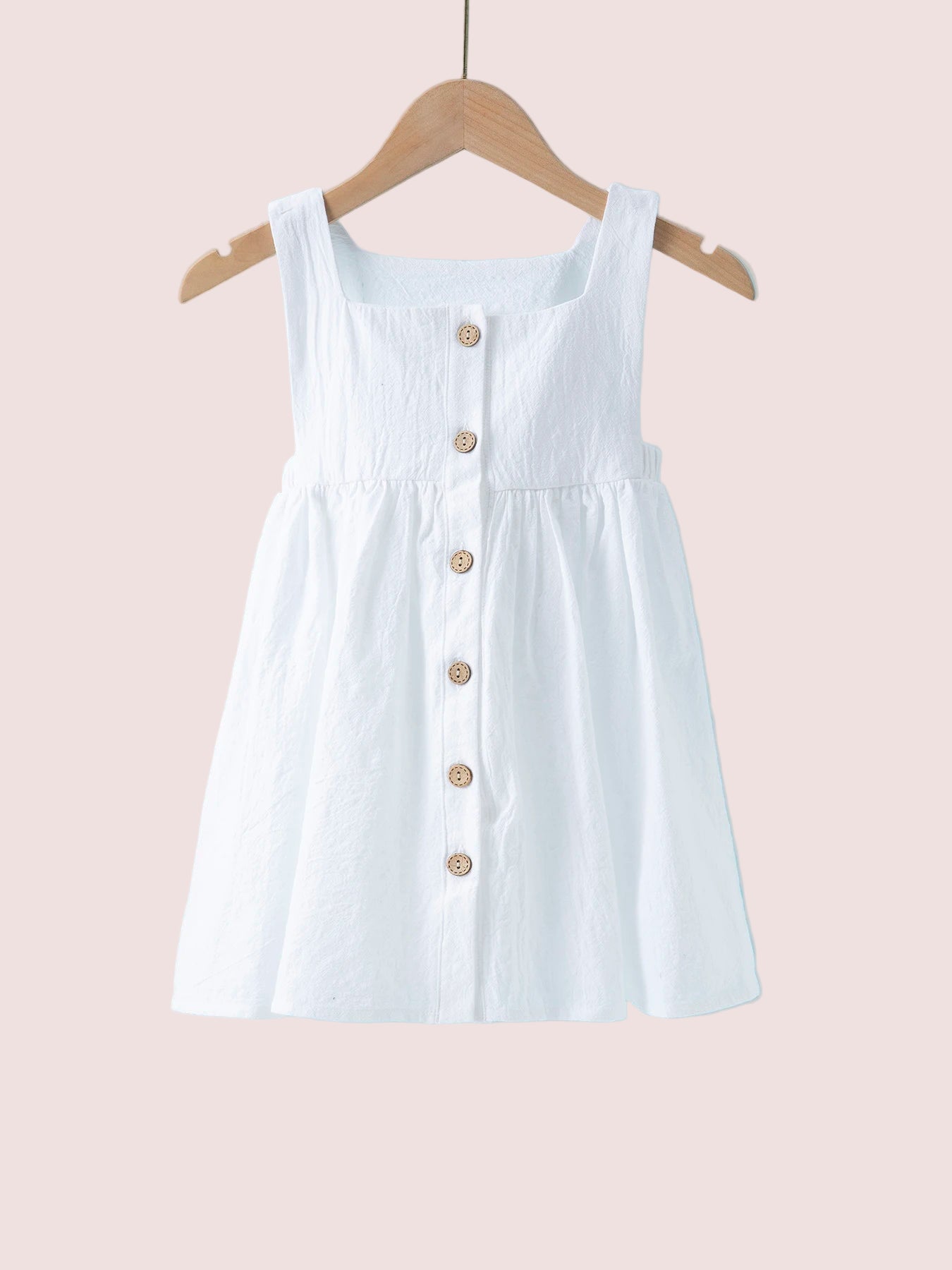 White dress with buttons on a hanger against a light blue background